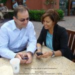 A man and woman sitting at a table looking at their cell phones.