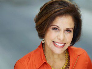 A smiling woman in an orange shirt.