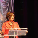 A woman giving a speech at a podium.