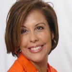 A smiling woman in an orange jacket.