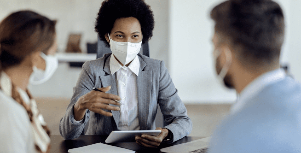 A person wearing a white facemask while talking to another person